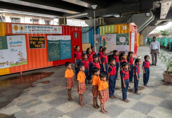 Des élèves chantent l'hymne national indien à "l'école du feu rouge" qui accueille des enfants défavorisés dans des conteneurs aménagés en salles de cours sous un pont autoroutier, le 18 mai 2026 à Bombay