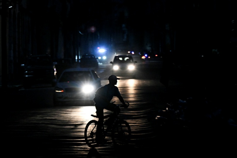 Un homme circule à vélo dans une rue pendant une coupure de courant à La Havane, le 1er août 2026