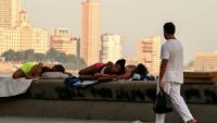 Un homme passe devant des femmes qui dorment sur le Malecon à La Havane lors d'une coupure de courant nationale, le 3 août 2026