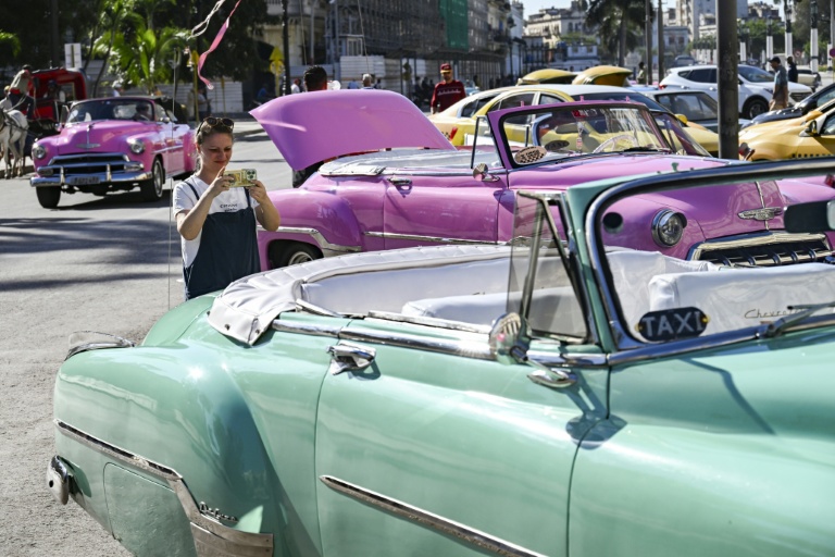 Une touriste prend en photo une voiture américaine dans une rue de La Havane, le 11 février 2026 à Cuba