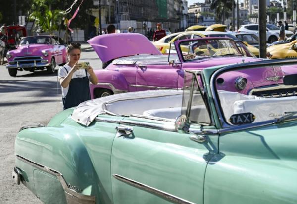 Une touriste prend en photo une voiture américaine dans une rue de La Havane, le 11 février 2026 à Cuba
