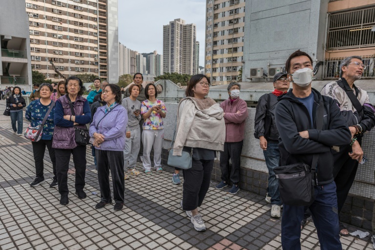 Des habitants observent des appartements encore en flammes après un violent incendie qui a ravagé plusieurs immeubles du complexe résidentiel Wang Fuk Court à Hong Kong, le 27 novembre 2025 