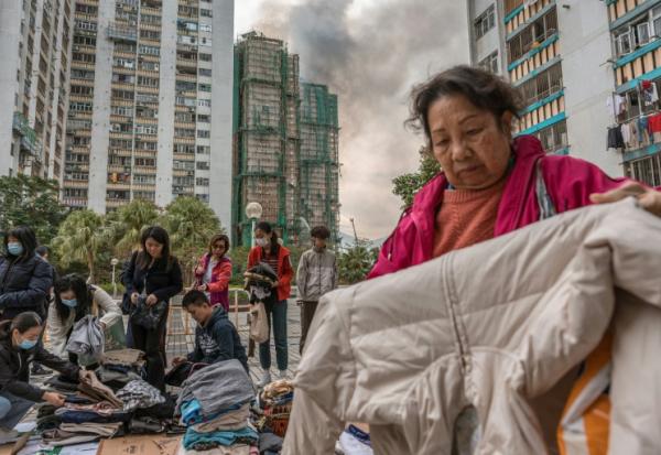 Des habitants trient des vêtements qui leur ont été donnés après qu'un important incendie a ravagé plusieurs immeubles d'appartements du complexe résidentiel Wang Fuk Court à Hong Kong, le 27 novembre 2025


