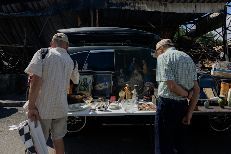 Des visiteurs regardent un étal du marché aux puces de Potchaiïna à Kiev, endommagé par une  une frappe russe, le 9 août 2026 à Kiev, en Ukraine