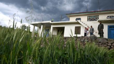 Mohammad Rashid (d) devant sa maison, surmontée d'un bunker récemment construit, dans le village de Kasaliyan, près de la frontière avec le Pakistan, le 6 avril 2026 en Inde