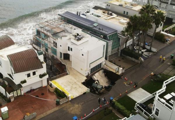 Vue aérienne montrant un gouffre apparu dans la rue et l'allée d'une maison en bord de mer, endommagée par les fortes houles provoquées par l'ouragan Marie à Malibu, en Californie, le 8 septembre 2026