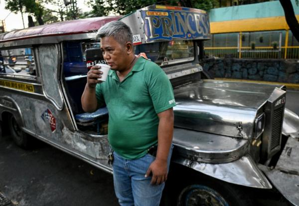 Le chauffeur de jeepney Eric Helera boit un café pendant une pause avant de prendre la route à Manille, le 23 mars 2026