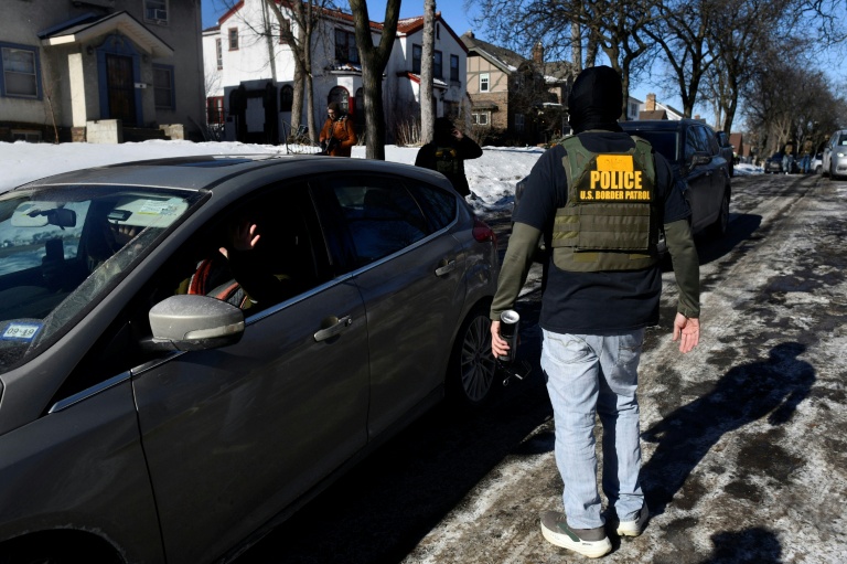 Des agents de l'Immigration (ICE)  face à des observateurs qui surveillent leurs activités depuis leurs voitures alors qu'ils patrouillent dans un quartier de Minneapolis, dans le Minnesota, le 29 janvier 2026