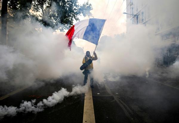Un manifestant agite un drapeau français au milieu des gaz lacrymogènes lors d'une nouvelle manifestation contre la vie chère, le 31 octobre 2026 à Lyon