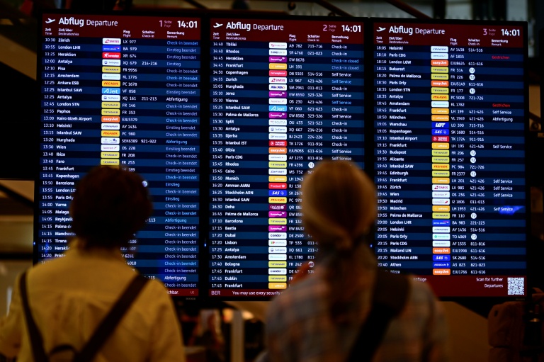 Des passagers regardent des panneaux d'affichage à l'aéroport Berlin-Brandebourg, le 20 septembre 2025 à Schoenefeld, au sud-est de la capitale allemande