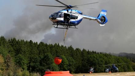 Des hélicoptères de la police chargent de l'eau pour lutter contre un incendie de forêt à Hurtgenwald, dans l'ouest de l'Allemagne, le 14 août 2026