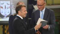Le chancelier allemand Friedrich Merz (D) et le président français Emmanuel Macron écoutent les explications d'un colonel à leur arrivée sur la base aérienne de Nörvenich, dans l’ouest de l'Allemagne, le 17 juillet 2026, où ils assisteront à une réunion du conseil de sécurité franco-allemand dans le cadre du conseil des ministres franco-allemand.