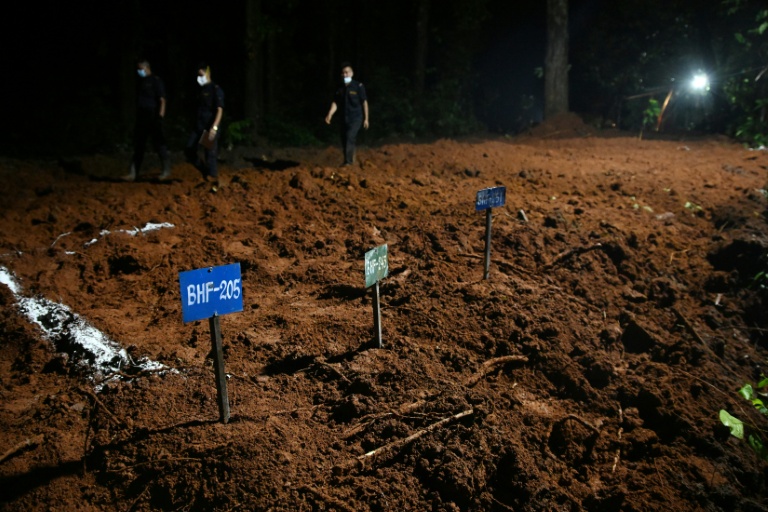 Des agents de police marchent à proximité de tombes de victimes non identifiées de la crue dévastatrice, le 30 août 2026 à Devghat au Népal