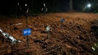 Des agents de police marchent à proximité de tombes de victimes non identifiées de la crue dévastatrice, le 30 août 2026 à Devghat au Népal