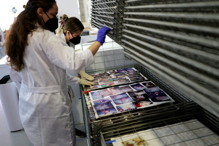 Des étudiants de l'Université des Beaux-Arts nettoient et restaurent des photos de famille par la boue pendant les inondations, le 2 octobre 2025 à Valence, en Espagne