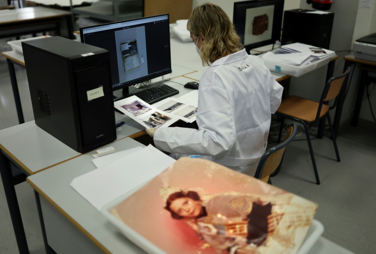 Une étudiante de l'Université des Beaux-Arts numérise des photos de famille endommagées par la boue pour les restaurer un an après les inondations à Valence, le 2 octobre 2025 en Espagne