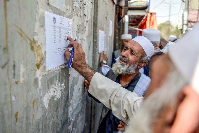 Un retraité vérifie une liste devant un bâtiment gouvernemental à Kabou, le 25 août 2025 en Afghanistan