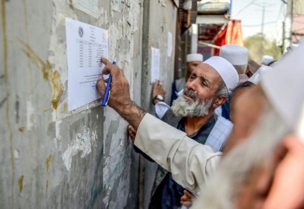 Un retraité vérifie une liste devant un bâtiment gouvernemental à Kabou, le 25 août 2025 en Afghanistan