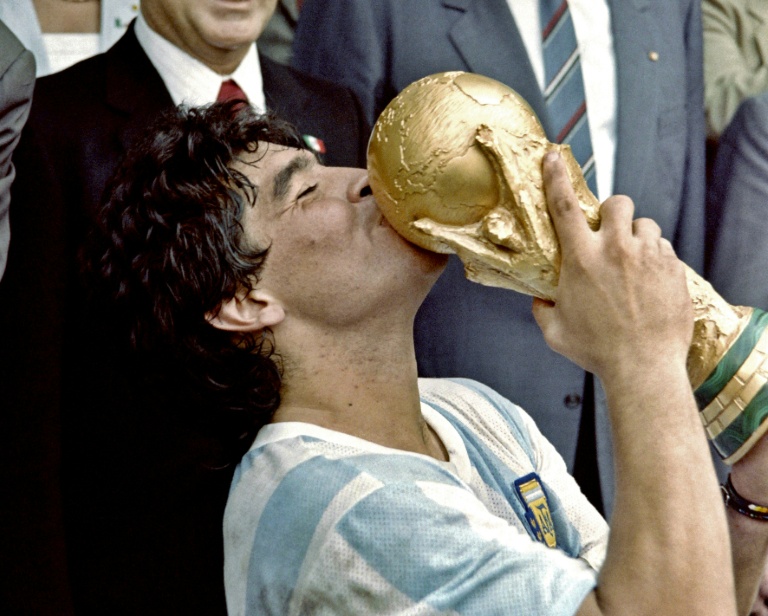 Sur cette photo prise le 29 juin 1986, la star du football argentin et capitaine de l'équipe, Diego Maradona, embrasse la Coupe du monde remportée par son équipe après une victoire 3-2 contre l'Allemagne de l'Ouest au stade Azteca à Mexico