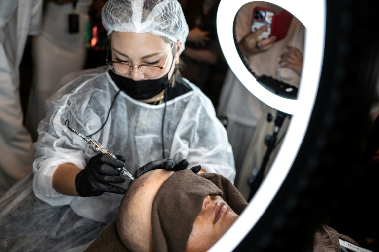 Un tatoueur spécialisé dans le tatouage du cuir chevelu lors d'un concours à Naha, dans la préfecture d'Okinawa, au Japon, le 8 juillet 2026
