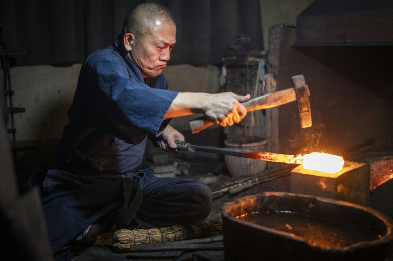 Le forgeron Akihira Kawasaki martèler de l'acier pour forger une lame de katana dans son atelier à Misato, le 9 janvier 2026 au Japon