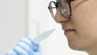L'élève parfumeur Shangyun Lyu sent une bande odorante utilisée pour évaluer les parfums dans le laboratoire du chimiste allemand Symrise, à Holzminden, le 8 juillet 2025 en Allemagne