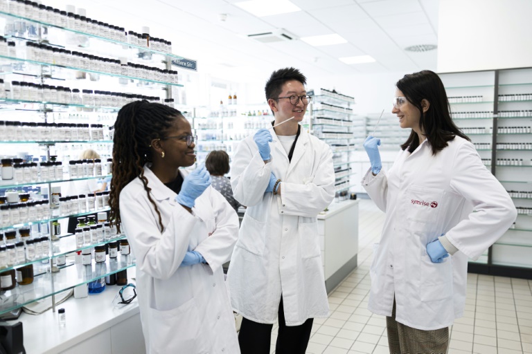 (g-d) Les élèves parfumeurs Attiya Setai, Shangyun Lyu et Alicia de Benito Cassado sentent des bandelettes odorantes utilisées pour évaluer les parfums dans une salle de mélange du laboratoire du chimiste allemand Symrise, le 8 juillet 2025 à Holzminden, en Allemagne