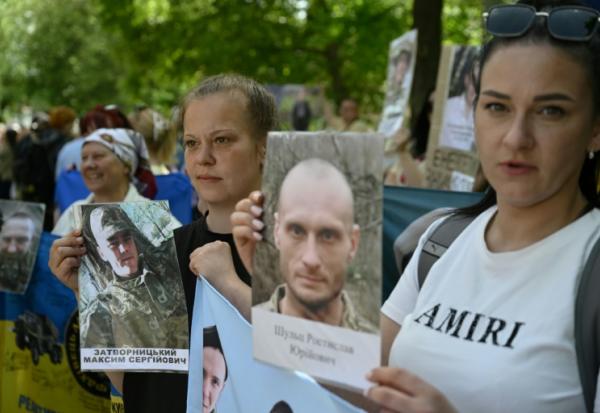 Des Ukrainiens brandissent des portraits de leurs parents captifs ou disparus dans l'espoir qu'ils seront reconnus par l'un ou l'autre des prisonniers de guerre libérés dans le cadre d'un échange avec la Russie, le 23 mai 2025 