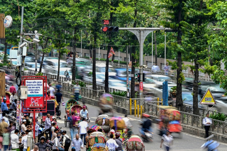 Des automobilistes passent près d'un système de contrôle du trafic basé sur l'intelligence artificielle dans la capitale bangladaise Dacca, le 14 mai 2026  