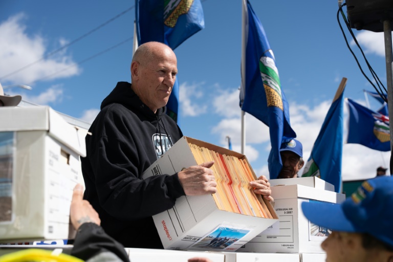 Le chef de file des séparatistes de l'Alberta Mitch Sylvestre, tenant un carton contenant des petitions demandant la tenue d'un vote, le 4 mai 2026 devant les locaux d'Elections Canada, à Edmonton (Canada).