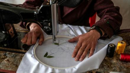 La couturière Rahima Alavi brode à la machine à coudre un tissu dans sa boutique à Bamiyan, le 26 janvier 2026 en Afghanistan