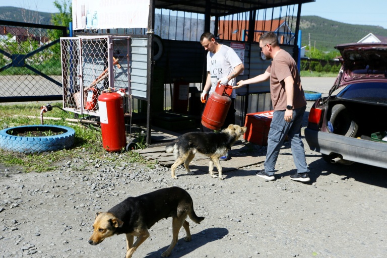 Iaroslav Voronov, vendeur dans un magasin d'électroménager, fait remplir une bouteille de gaz dans une station-service à Chtchoutchinsk, le 27 mai 2026 au Kazakhstan