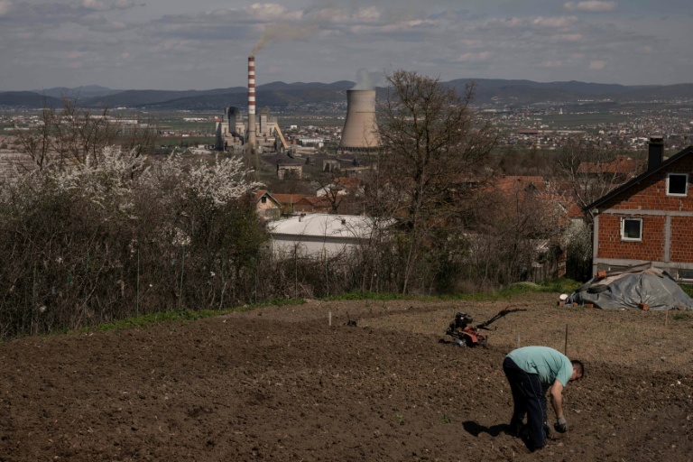Un homme travaille dans son jardin qui surplombe une centrale thermique au charbon, près de la ville d'Obilic, au Kosovo, le 10 avril 2026