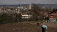 Un homme travaille dans son jardin qui surplombe une centrale thermique au charbon, près de la ville d'Obilic, au Kosovo, le 10 avril 2026