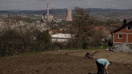 Un homme travaille dans son jardin qui surplombe une centrale thermique au charbon, près de la ville d'Obilic, au Kosovo, le 10 avril 2026