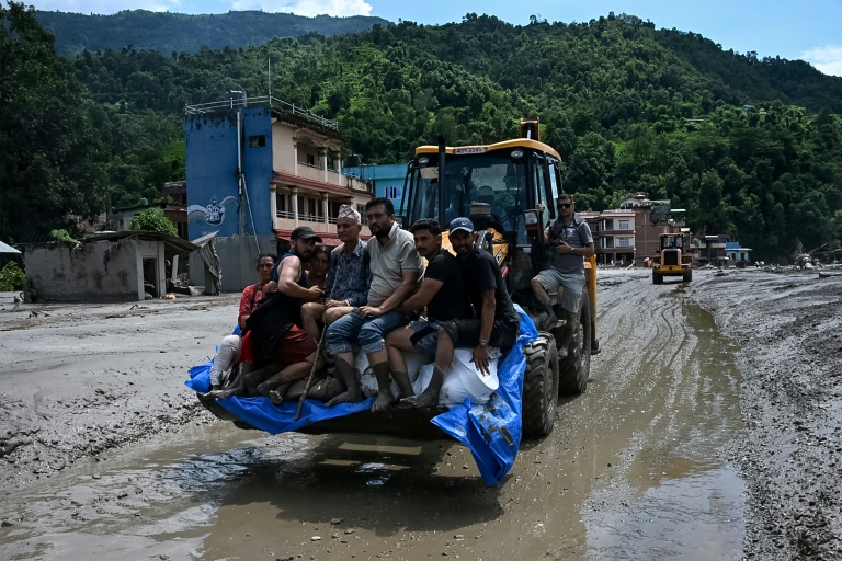 Des sauveteurs transportent des habitants bloqués à l’aide d’un bulldozer après des crues soudaines dans la région de Devighat, dans le district de Nuwakot au Népal, le 27 août 2026