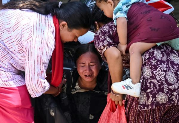 Une femme s’effondre tandis qu’elle attend l’arrivée de ses proches dans un camp militaire après avoir été secourue des zones touchées par des crues subites, dans la ville de Battar Bazar, dans le district de Nuwakot au Népal, le 27 août 2026