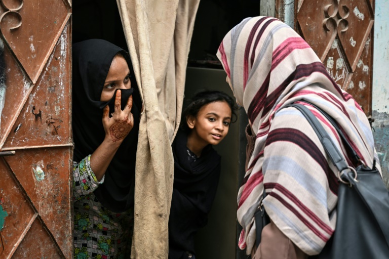 Une agente de santé parle à une femme et sa fille, lors d'une campagne de vaccination porte-à-porte contre le virus du papillome humain (VPH) responsable du cancer du col de l'utérus, le 24 septembre 2025 à Karachi, au Pakistan