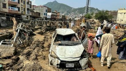 Des habitants de Mingora sont réunis autour d'un véhicule endommagé et de débris après l'effondrement de la route suite aux crues subites dans la province montagneuse de Khyber Pakhtunkhwa au Pakistan le 16 août 2025