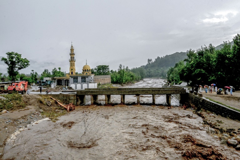 Des villageois (d) se tiennent près d'un pont alors que le niveau des eaux de crue monte dans le district de Buner, dans la province  de Khyber Pakhtunkhwa, le 18 août 2025 au Pakistan