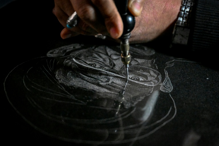 L'artiste Sadiq Poya grave le portrait d'une personne décédée sur une pierre tombale à Quetta, au Pakistan, le 17 février 2026