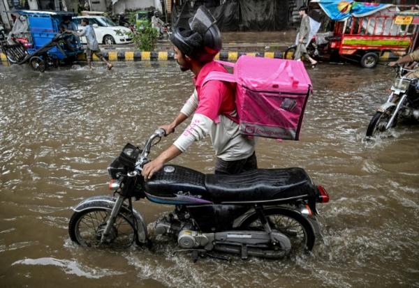 Abdullah Abbas, livreur de repas, pousse sa moto dans une rue inondée après de fortes pluies à Lahore, le 30 août 2025 au Pakistan