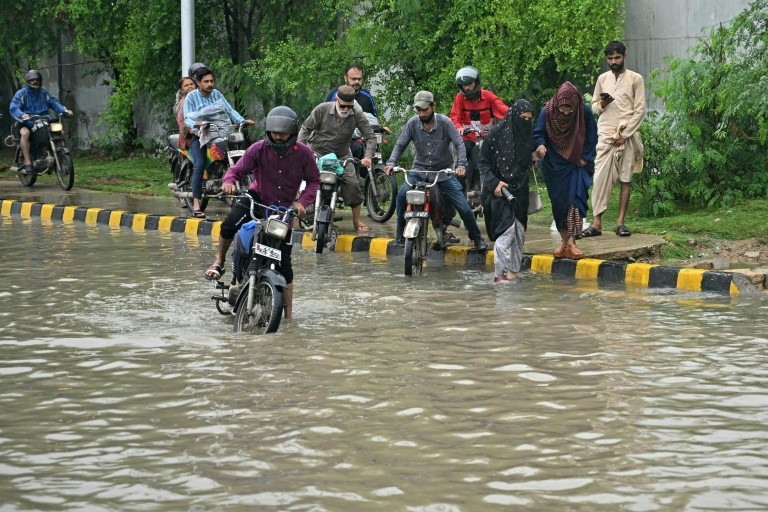 Des habitants tentent de passer à moto dans une rue inondée après de fortes pluies, le 10 septembre 2025 à Karachi, au Pakistan