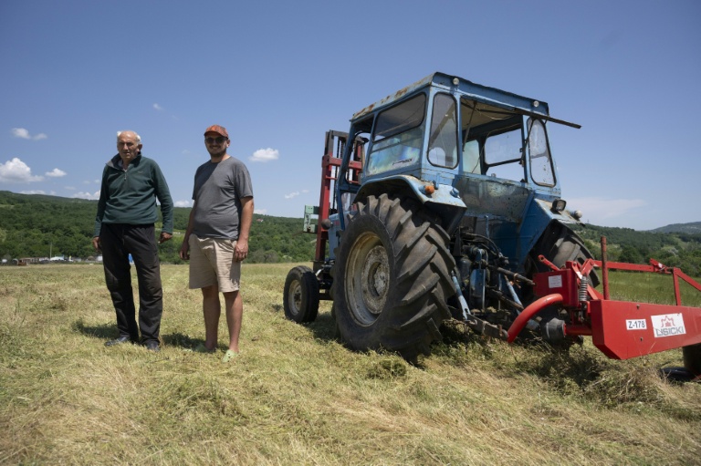 Emil Deliev, éleveur bulgare de 58 ans (G), et son fils Denislav Deliev, 29 ans, posent à côté d'un tracteur dans leur exploitation située près du village de Sofiytsi, dans la commune de Dzhebel, au sud-est de la Bulgarie, le 9 juin 2026