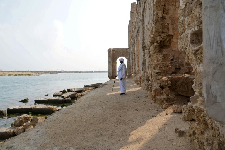 Un homme se tient face à la mer, devant une ruine dans le port soudanais de Suakin, le 22 janvier 2026