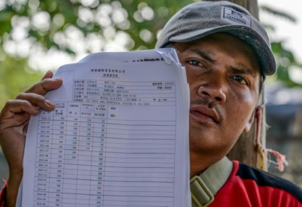 Akhmad, ancien membre d'équipage d'un navire de pêche chinois, montre son contrat et son salaire mensuel lors d'un entretien avec l'AFP au port du hameau de Bungko Lor, à Cirebon, le 10 juin 2026 en Indonésie