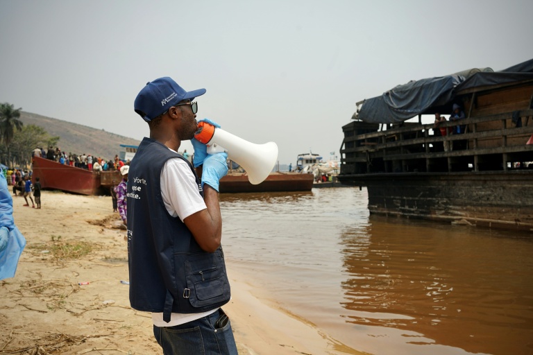 Mégaphone à la main, Yves Matwa, agent de la riposte à Ebola, passe les consignes aux passagers d’une baleinière, au port de Bende-Bende, commune de Maluku, à 70 km au nord-est de Kinshasa, le 20 août 2026