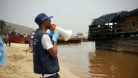 Mégaphone à la main, Yves Matwa, agent de la riposte à Ebola, passe les consignes aux passagers d’une baleinière, au port de Bende-Bende, commune de Maluku, à 70 km au nord-est de Kinshasa, le 20 août 2026