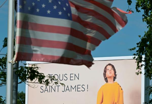 Une affiche publicitaire derrière un drapeau américain à côté de l'usine Saint-James, dans la Manche, le 22 mai 2025