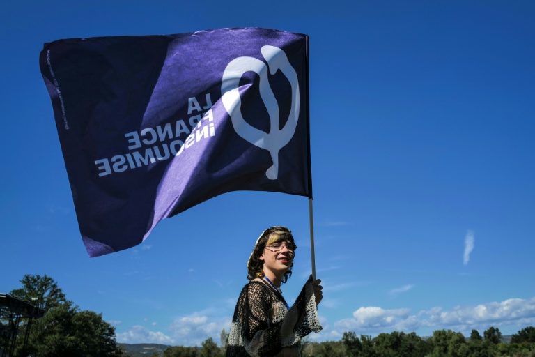 Une sympathisante de La France insoumise (LFI) tient un drapeau lors des universités d'été du parti (LFI), le 22 août 2026 à  Châteauneuf-sur-Isère, dans la Drôme 